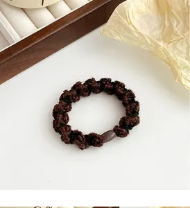 Détail du chouchou en maille marron avec perle ovale polie et texture en spirale