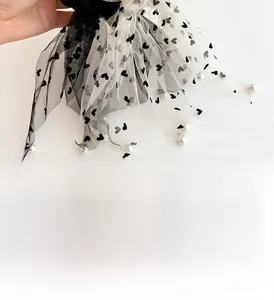 Dettaglio elastico in tulle con cuori, pois e piccole perle bianche decorative