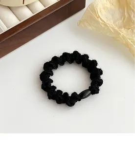 Vue détaillée d'un élastique à cheveux en tricot noir avec boucle en résine sur blanc