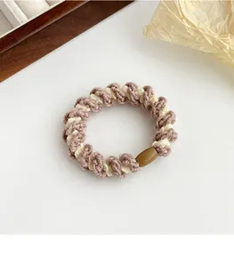 Détail de l'élastique à cheveux en spirale tissé rose et crème avec un fermoir marron poli