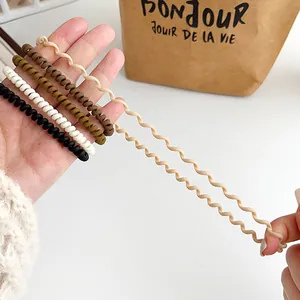 Elastic matte spiral hair ties in neutral tones shown being stretched for flexibility
