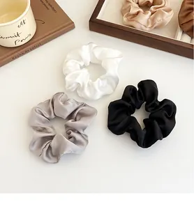 Détail de chouchous en satin de soie assortis sur un plateau en bois avec décor élégant