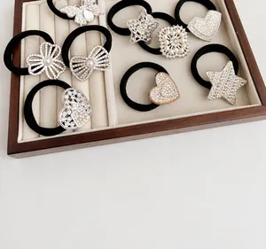 Detailed view of rhinestone bow and heart charms on black high-elastic hair ties
