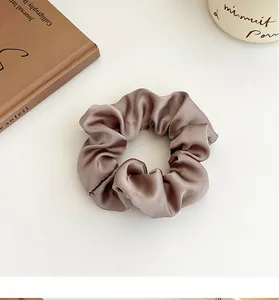 Gros plan sur un chouchou en satin de soie marron moka avec des plis élégants pour cheveux