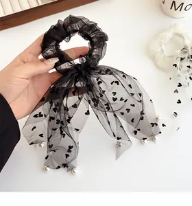 Dettaglio elastico in tulle nero con cuori e nastri decorati con perle bianche