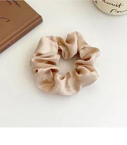 Détail du chouchou en satin champagne avec texture soie et plis élégants