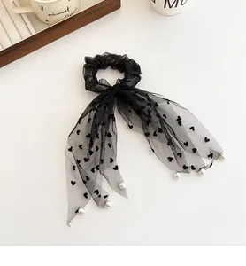 Dettaglio dell'elastico in rete nera con nastri a cuori e decorazioni di perle