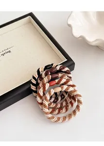 Detailopname van vijf spiraalvormig geweven haarelastiekjes met decoratieve kralen