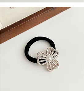 Détail de l'élastique à cheveux noir avec pendentif fleur dorée, cristaux et perle