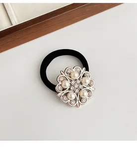 Détail macro d'un élastique à cheveux avec fleur argentée, perles et strass brillants