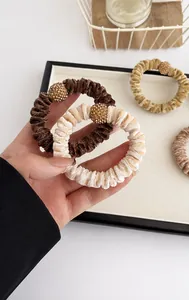 Close-up of velvet scrunchies with rhinestone ball charms in earthy coffee tones