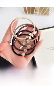 Dettaglio di 5 elastici per capelli cuore con strass in tonalità terra e caffè