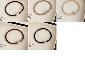 Dettaglio di elastici per capelli in cinque colori neutri con cuori di strass lucidi