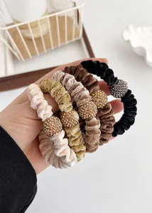 Detail of five velvet scrunchies with sparkling rhinestone balls in neutral earthy tones
