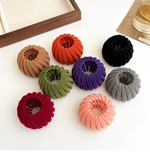 Flat lay of eight colorful flocked bird nest hair clips on a minimalist beige background