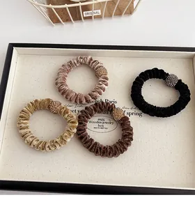 Close-up of velvet hair scrunchies set with rhinestone ball charms in jewelry tray