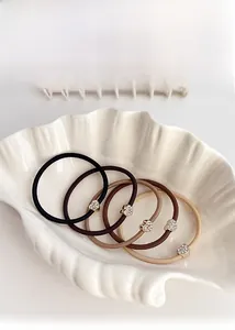 Dettaglio di cinque elastici per capelli con ciondoli a cuore in strass e toni terra