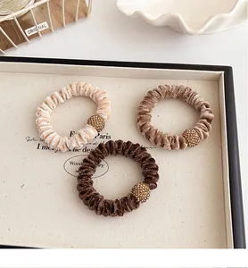 Detail of velvet scrunchies with rhinestone gold beads in cream and brown tones
