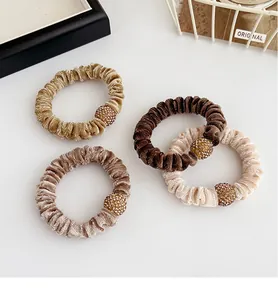 Close-up of four velvet scrunchies with rhinestones in coffee and champagne tones