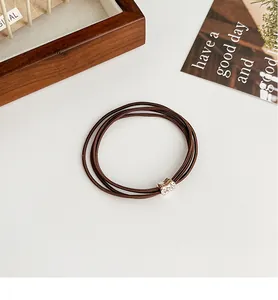 Close-up of four-strand dark brown elastic hair tie with sparkling rhinestone metal buckle