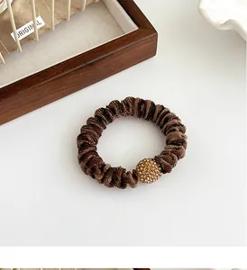 Detail of dark brown velvet scrunchie with champagne rhinestone ball decoration