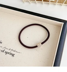 Dettaglio di un ciondolo a cuore con strass scintillanti su un elastico per capelli viola