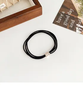 Detail of black multi-strand hair tie featuring a gold rhinestone-encrusted buckle