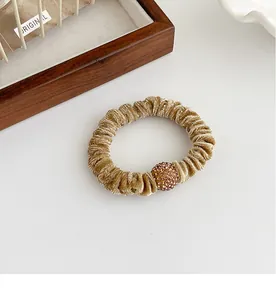 Detailed view of champagne velvet scrunchie texture with sparkling rhinestone ball