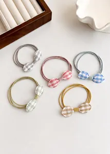 Flat lay of five checkered bow hair ties in soft pastel colors on a white surface