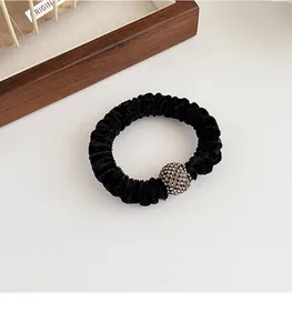 Detail of black velvet scrunchie featuring a sphere bead studded with sparkling rhinestones