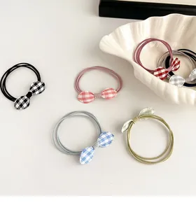Detail of multi-color gingham bow hair ties in a shell plate for girls styling