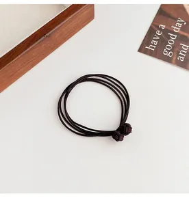 Detailed macro view of durable elastic hair ties with woven ball knots in dark brown finish