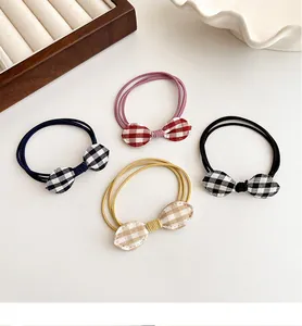 Close-up of four plaid bow hair ties in red, blue, black and beige on a jewelry tray
