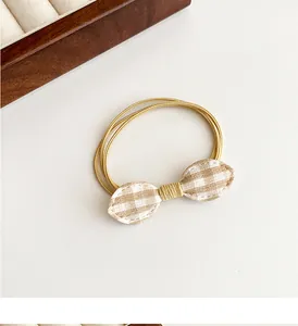 Close-up of beige elastic hair ties with a cute brown plaid fabric bow detail