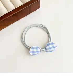 Detail of blue and white gingham bow hair tie made with multi-strand elastic band