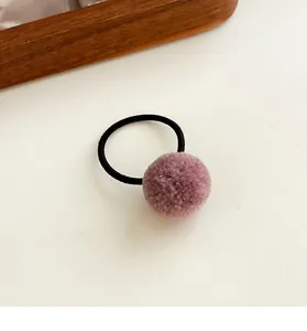 Close-up of a pink plush pom pom hair tie with high elasticity black rubber band