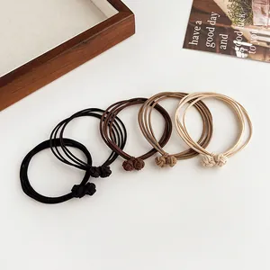 Minimalist elastic hair ties set in earthy tones on a white table with soft lighting