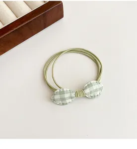 Detail of light green elastic hair tie with small green and white checkered fabric bow