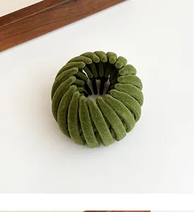 Close-up of a dark green flocked bird nest hair clip with a velvet texture finish