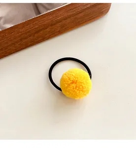 Detailed shot of a soft yellow pom pom hair tie with high-elastic black rubber band