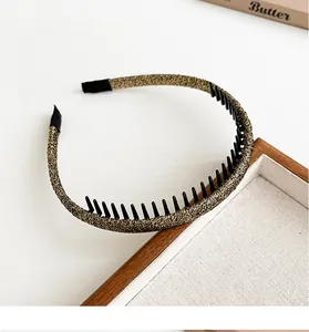 Detail van glitter gouden dunne haarband met zwarte antislip kamtanden op houten blad