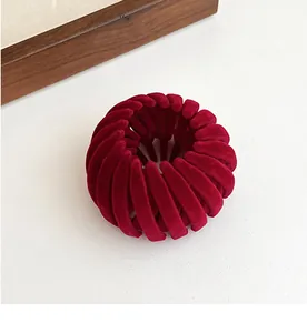 Detailed top view of a dark red flocked expandable bird nest hair clip on a white base