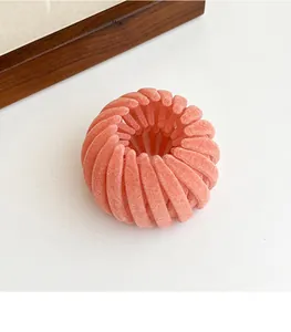 Detail showing coral pink velvet flocked birds nest telescopic hair clip on a clean surface