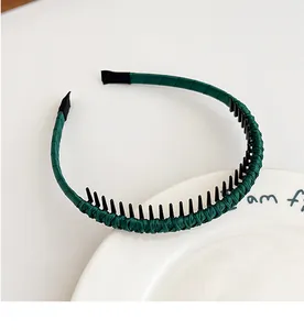 Détail du serre-tête en tissu vert foncé avec dents antidérapantes sur assiette blanche