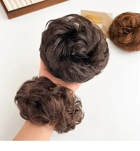 Detailweergave van pluizige kunstmatige knot-haarelastiekjes in drie natuurlijke tinten