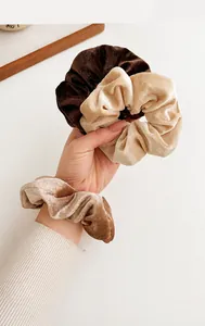 Detailoverzicht van pluche fluwelen haarscrunchies in aardetinten vastgehouden in de hand