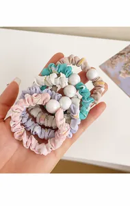 Gros plan de chouchous à fleurs et unis avec grosses perles en cinq couleurs pastel
