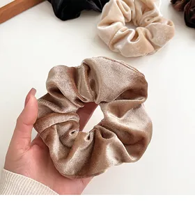 Detailopname van champagne goud fluwelen scrunchie met zachte textuur en glanseffect