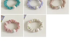 Détail de cinq chouchous à fleurs aux couleurs variées avec de grandes perles élégantes