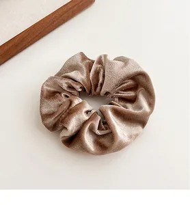 Detailopname van champagne fluwelen scrunchie met luxe textuur en zachte golfplooien